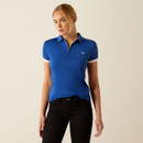 A woman in a blue polo shirt and black pants stands against a neutral background. She looks to the side, conveying a calm and confident tone.
