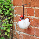 A hen shaped wool dispenser hanging from a hook.