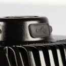 Close-up of a black device with a USB symbol embossed on a rubber cover. The shiny surface and metal fins suggest a modern electronic component.