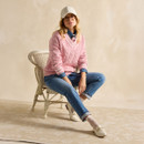 Person in a pink jumper and jeans sitting on a wicker chair.