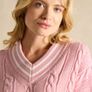 Person in a pink cable knit jumper with a V-neck collar and blonde hair.