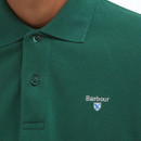 A close up of a man wearing a dark green polo with a buttoned up collar