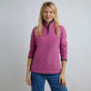 A woman wears a vibrant pink zip-up fleece with a textured design, paired with blue denim jeans, against a light background.