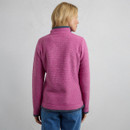 A person wearing a pink textured fleece with a blue collar, viewed from the back, standing against a light gray background.