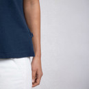 A close-up of a person wearing a navy blue t-shirt, showcasing the fabric, sleeve detail, and a white pants against a light background.