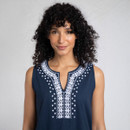 A person wearing a navy blue sleeveless top with intricate white embroidery along the neckline and shoulders, against a light backdrop.
