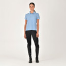 Person in a blue polo shirt, black leggings, and knee-high boots standing against a white background.
