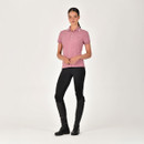 Person in a pink polo shirt, black leggings, and tall riding boots against a white background.