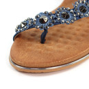 Detail close-up of navy blue embellished sandal strap with rhinestones and metallic studs over tan footbed.