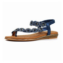 Angled view of navy blue rhinestone T-bar sandal with decorative strap detailing and tan footbed on a white background.
