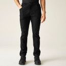 A person wearing black outdoor pants and hiking boots stands with hands in pockets, against a plain cream background, conveying a casual vibe.