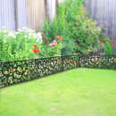 Lush garden corner with decorative metal fence and green grass.