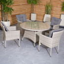Round wicker dining set with four cushioned chairs on a gray stone patio. Wooden fence and potted plants create a cosy outdoor ambiance.