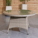 Round wicker outdoor table with a glass top on a gray tile floor. Wooden slat wall and potted plants in the background, creating a serene atmosphere.