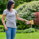 A view of a woman pouring cat and dog granules on a green lawn