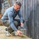 A view of a man setting up a rat cage outside