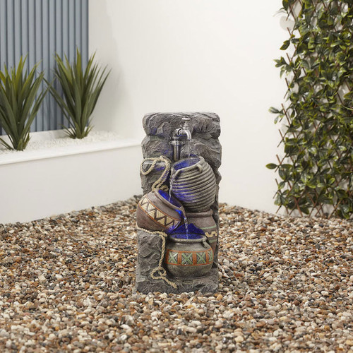 A water fountain with a tap pouring into the jugs below