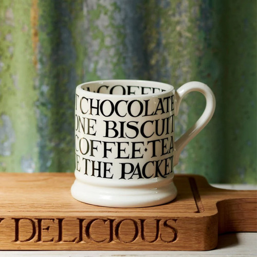 A view of a white mug with black writing on a wooden chopping board