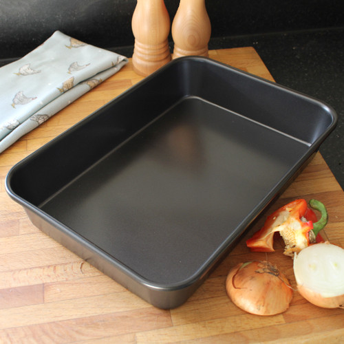 A grey metal roasting pan positioned on a cutting board.