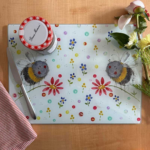 A whimsical worktop saver featuring illustrated bees and flowers, accompanied by a jar of jam, knife, and fresh blooms.