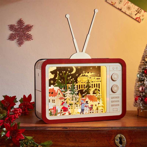 A vintage-style decorative television showcasing a festive winter scene with Santa, a snowman, and cosy houses, surrounded by holiday decor.