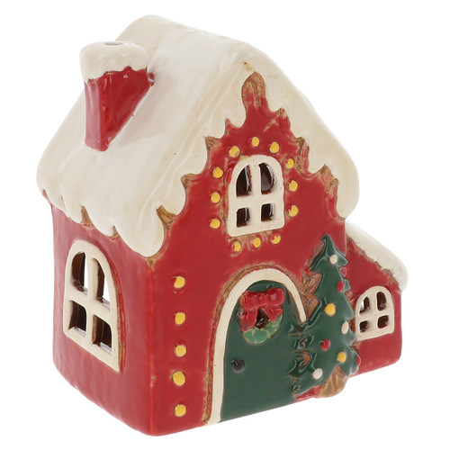 A small, festive red ceramic house with a white snow-covered roof, decorated with a green door and a Christmas tree.