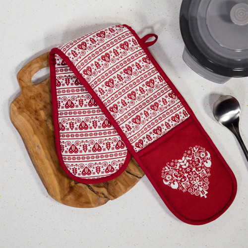 Red and white patterned oven gloves displayed on a wooden cutting board, alongside a spoon and a covered pot in the background.