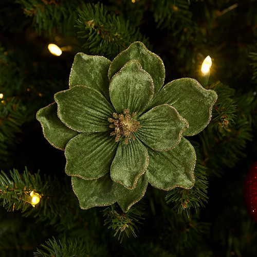 A textile green magnolia flower with gold glitter edging on a Christmas tree surrounded by lights.