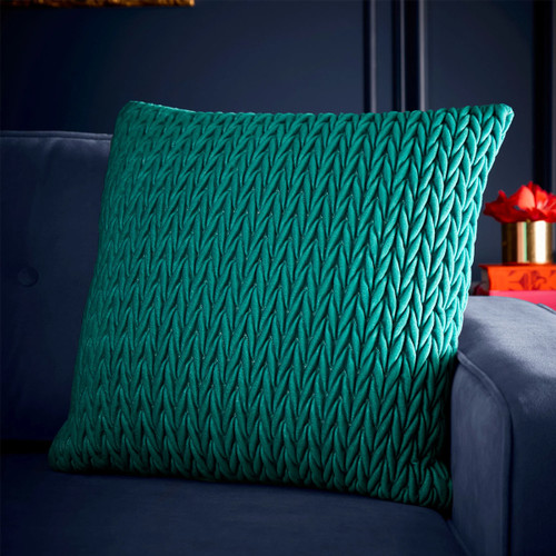 A view of a jade green cushion on a blue sofa