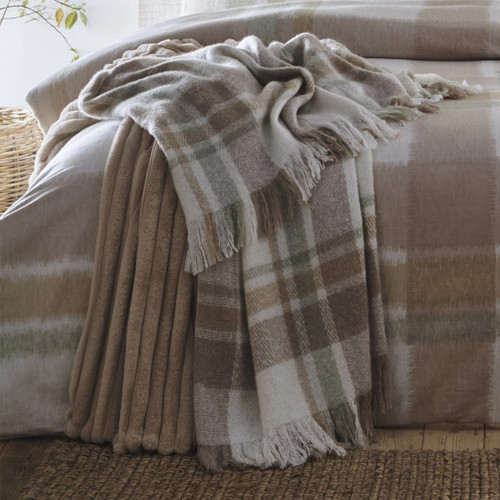 A view of a natural colour checked throw on the end of a bed