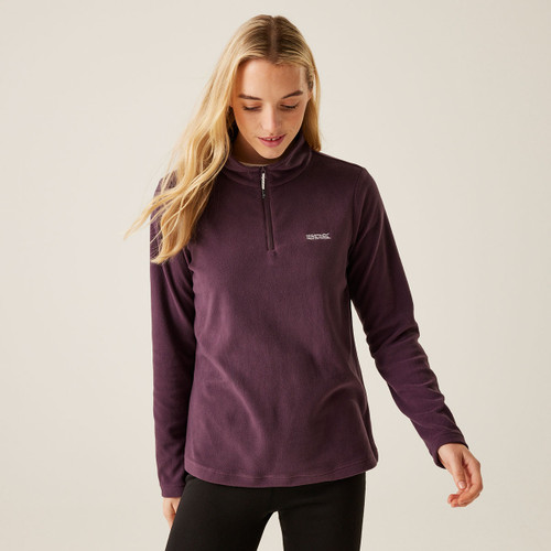 A woman wearing a deep plum coloured quarter zip fleece.