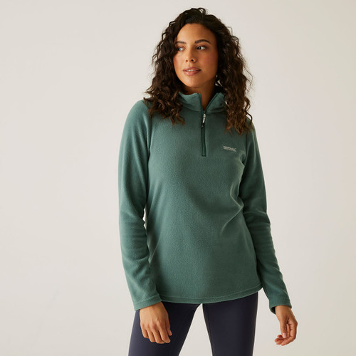 A woman wearing a deep green quarter zip fleece.