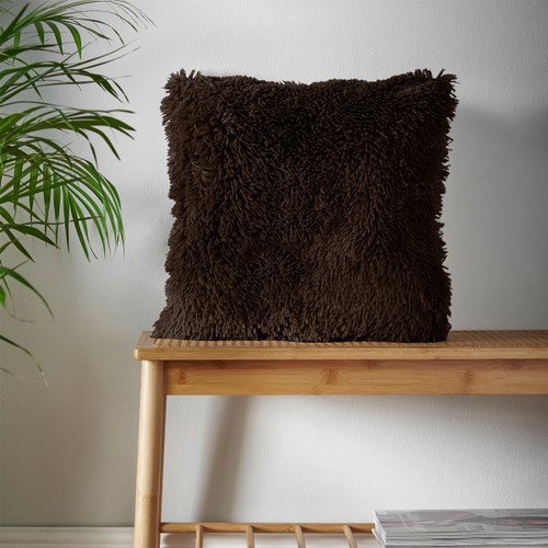 A view of a brown Catherine Lansfield fluffy cushion on a bench