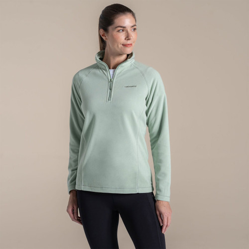 Woman wearing a mint green Craghoppers fleece pullover with half zip and high collar.