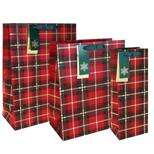 Three festive gift bags with red and black plaid patterns. Each bag has a green tag with a white snowflake and dark green handles, evoking a holiday theme.