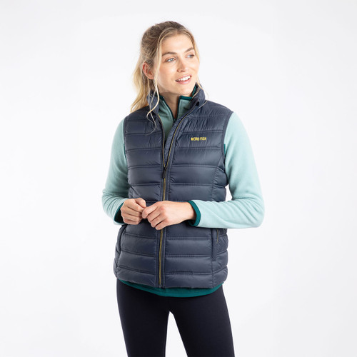 Woman wearing a navy blue quilted gilet with yellow “Weird Fish” branding on the chest.