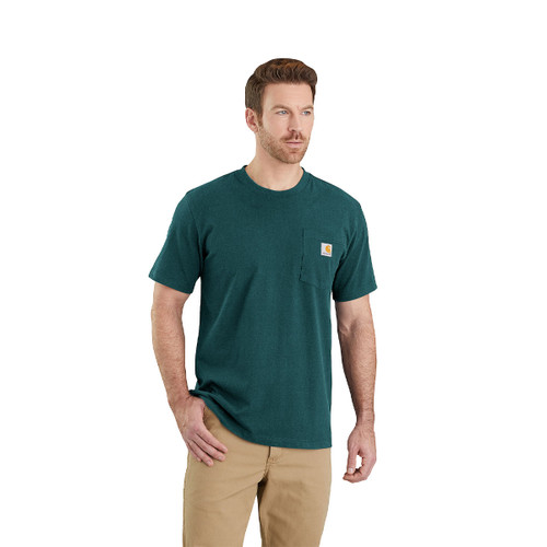 Man wearing a dark green Carhartt short-sleeved crew-neck T-shirt with a left chest pocket featuring the Carhartt logo, paired with beige trousers, standing against a white background.