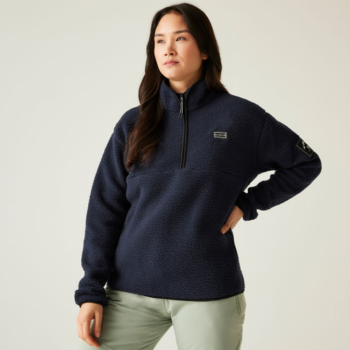 Front view of a woman wearing the navy Dare2b Slide Out Fleece with a half-zip and high collar, posing with one hand on her hip.