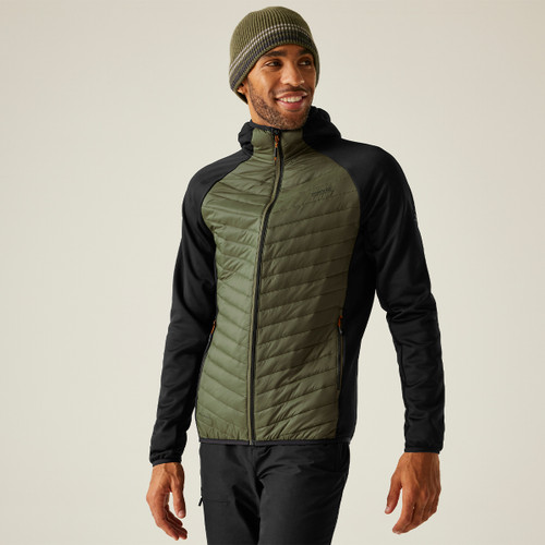 Man wearing a green quilted jacket with black sleeves and a green beanie, smiling confidently. Neutral background, casual and outdoorsy vibe.