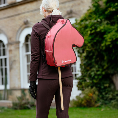 Child wearing the LeMieux Cranberry Hobby Horse Carry Bag outdoors, designed to hold and transport hobby horses with ease.
