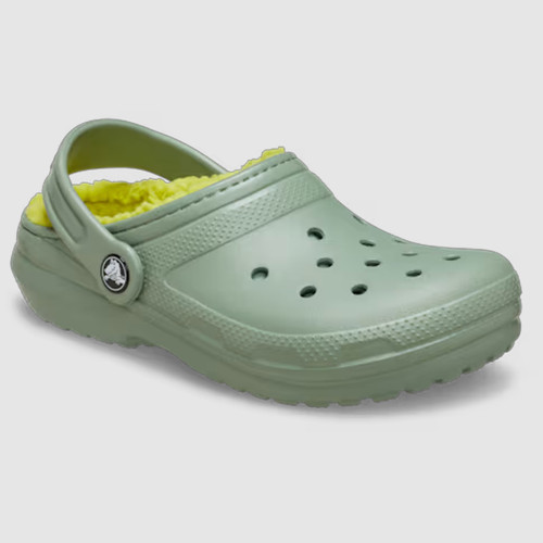 Green clog-style shoe with perforated holes, featuring a bright yellow fleece lining and an adjustable heel strap. The overall tone is cosy and functional.
