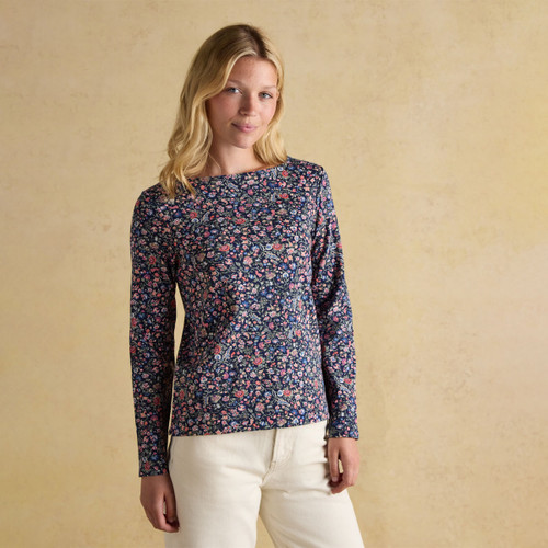 Woman wearing a navy floral long sleeve top with small pink and blue flowers, styled with off-white trousers.