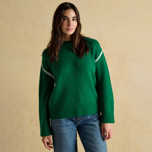 Woman wearing the Alexandra green jumper with relaxed fit and white stitching across the arms.
