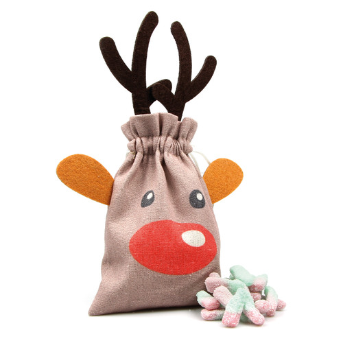 A festive drawstring bag designed like a reindeer, with antlers and a red nose, sits next to pastel-colored candy sticks, creating a playful holiday vibe.