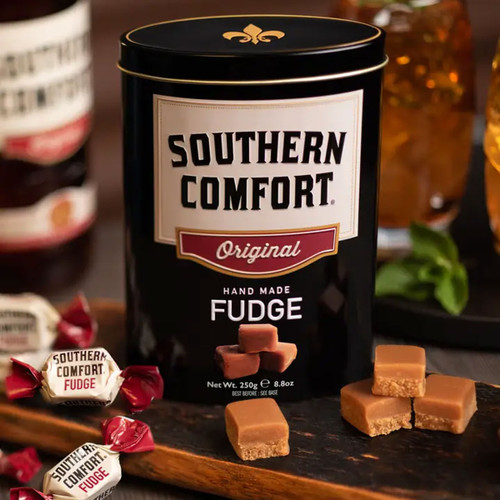 Southern Comfort Handmade Fudge 250g gift tin with creamy fudge pieces, presented with drinks in the background.