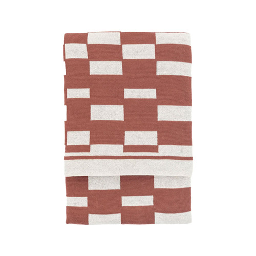 A folded nutmeg throw with a geometric block pattern.