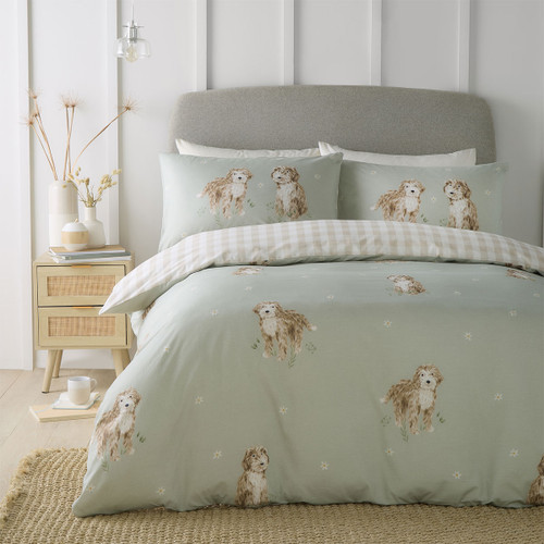 Cosy sage green bedding set with illustrated fluffy dog print and soft gingham reverse, styled in a modern bedroom.