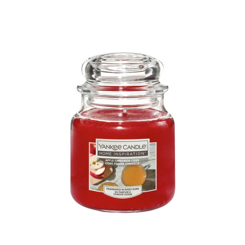 Red Yankee Candle in a glass jar labeled "Home Inspiration, Apple Cinnamon Cider." The design is cozy and evokes a warm, autumn ambiance.
