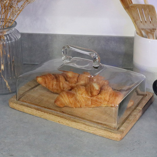A rectangular glass cake dome with handle and wooden base, displaying fresh croissants on a grey kitchen worktop.
