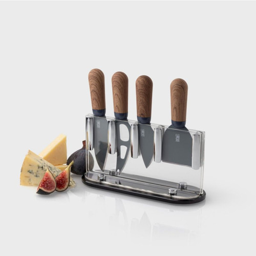 Four-piece cheese knife set with grey blades and wooden handles neatly stored in a transparent acrylic stand beside cheese and figs.